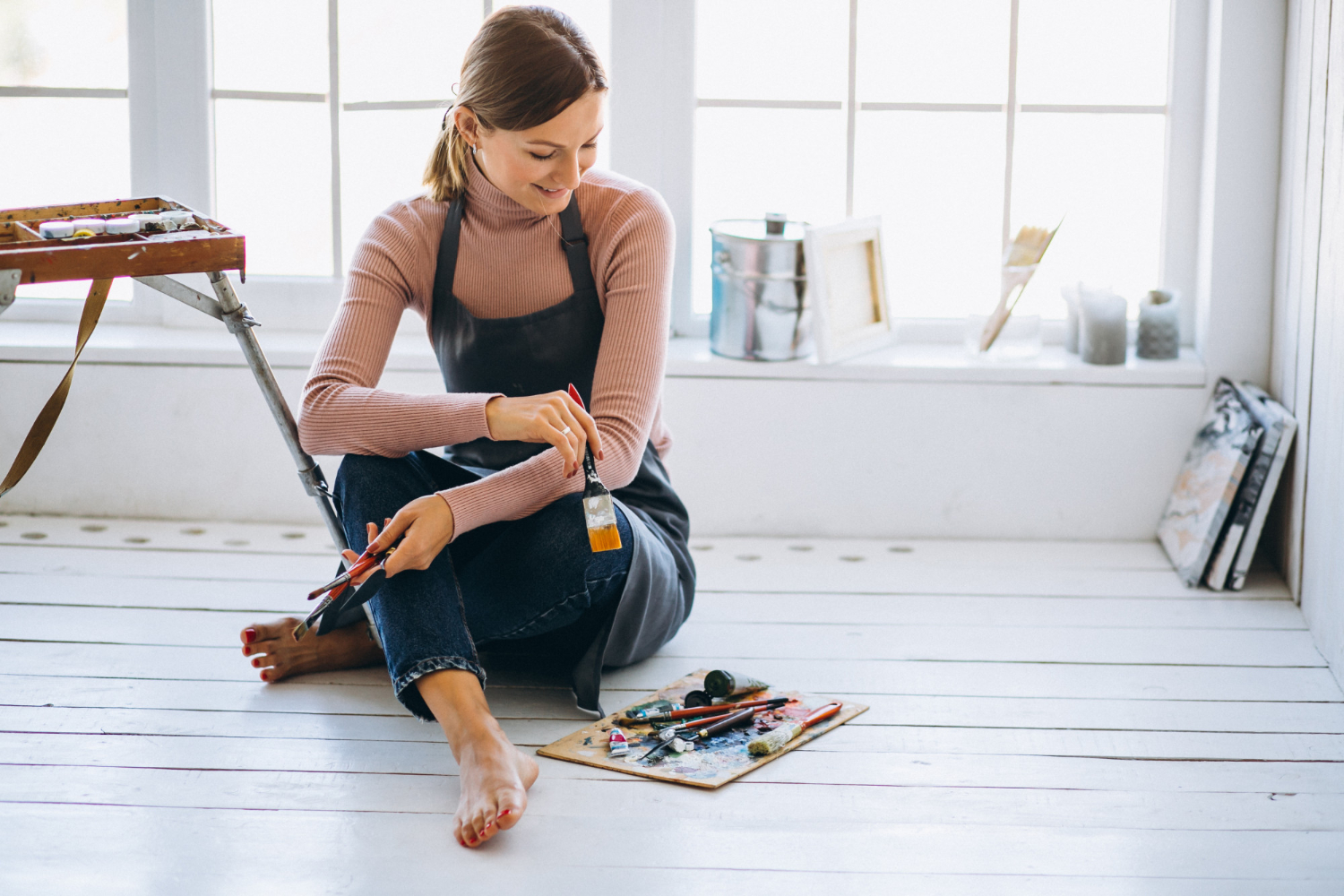 Mujer pintando el suelo de madera para renovar un piso antes de venderlo